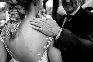 Man die een hand op de schouder van de bruid legt